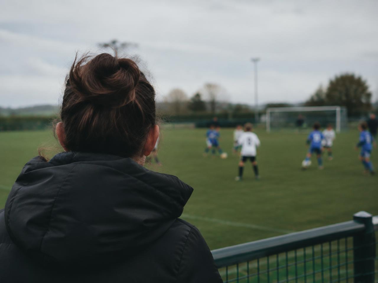 A parent watching a youth football match from the touchline